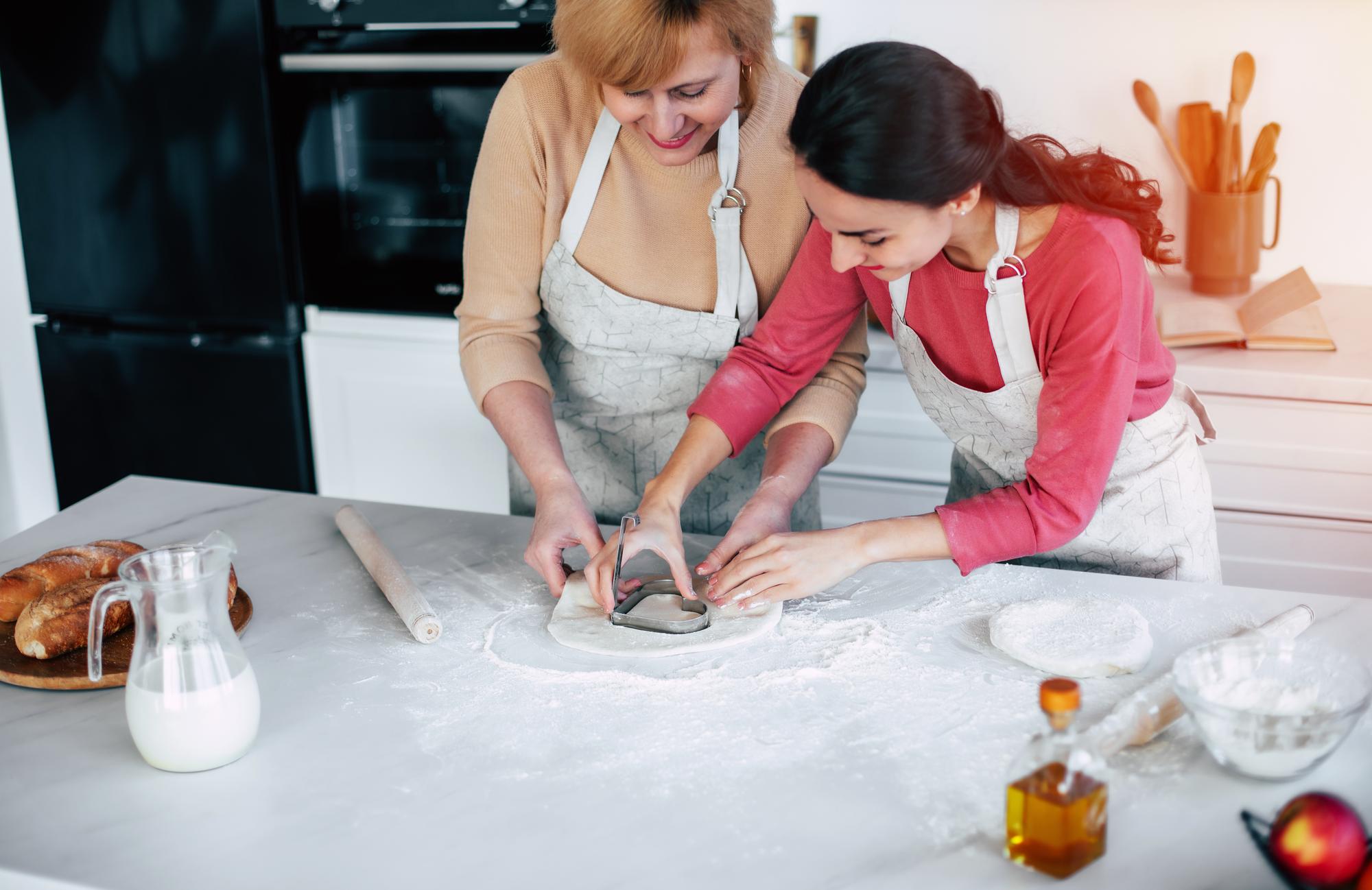 Chef instructor guiding a student in a home kitchen